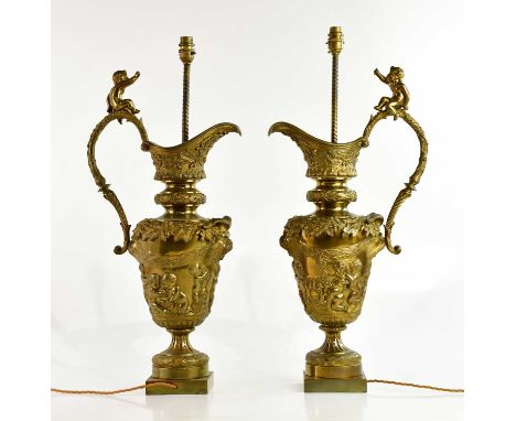 A pair of bronze table lamps representing ewers, with cast and relief decoration of cherubs, swags and detail, height includi
