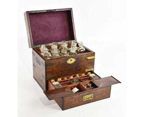 A Regency brass bound mahogany apothecary cabinet, the hinged cover enclosing an arrangement of sixteen bottles, some example