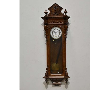 A late 19th century carved walnut three weight Vienna clock, the enamel dial set with Roman numerals, with pyramid shaped fin
