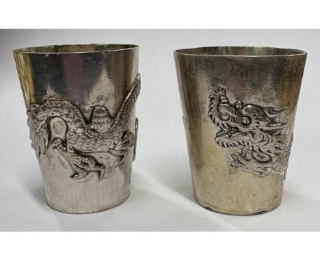 A pair of Chinese export silver stacking beakers embossed with dragon decoration. Approx. 52 grams. Est. £60 - £80.