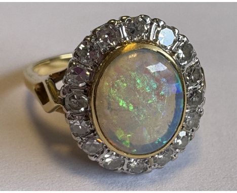 An opal and diamond oval cluster ring in 18 carat gold setting. Approx. ring size M 1/2. Approx. 5 grams. Est. £200 - £300.