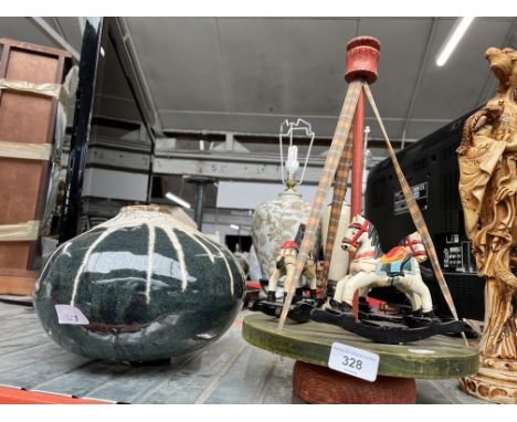 A vintage wooden carousel and a studio pottery vase. 