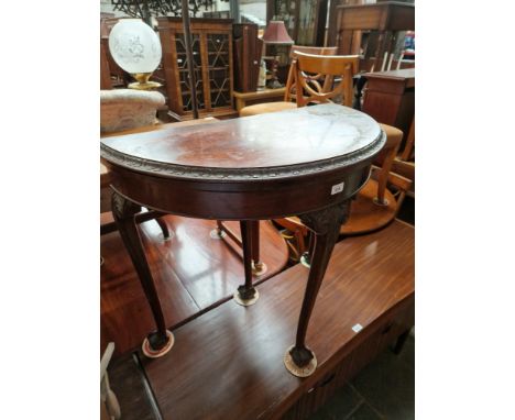 An early 20th century mahogany demi-lune card table on ball and claw feet. 