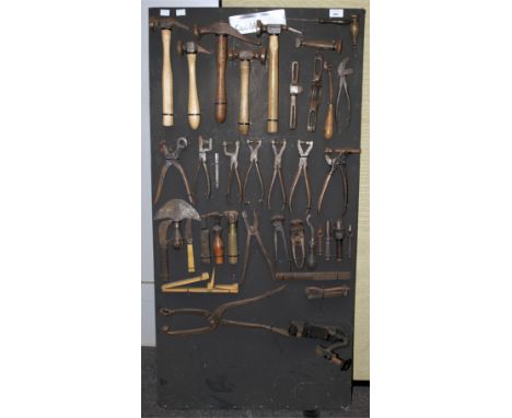 A collection of assorted vintage 'Cobbler' tools on a display board. Including five hammers, leather hole punches, etc.