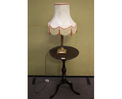 A Victorian mahogany occasional table and a brass table lamp. The table with a circular top, a turned central column and trip