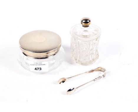 An assortment of silver. Comprising sugar nips, a silver topped jar with engine turned decoration and a silver mounted dressi