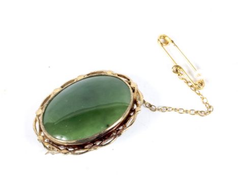 A vintage nephrite-jade oval brooch. The oval cabochon approx. 25mm x 18.5mm, millegrain set in yellow within an open bead an