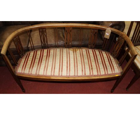 An Edwardian faded mahogany framed and striped pad seat upholstered twin salon sofa (well-worn and requires reupholstery), w.