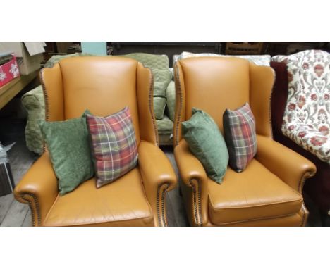 Pair of wing salon fireside chairs, the studded padded upholstery in light brown leather, each with 2 cushions