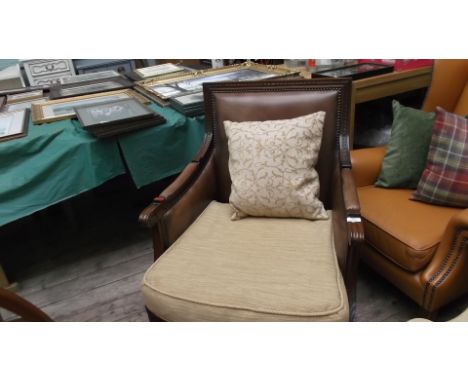 Carved oak framed armchair, the studded and padded arms, back and seat upholstered in light brown leather