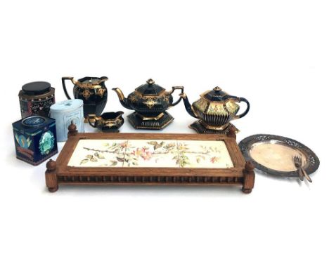 Two black and gilt teapots on stands, with milk jugs, a 19th century tiled stand, the tiles monogrammed PSE, and some vintage