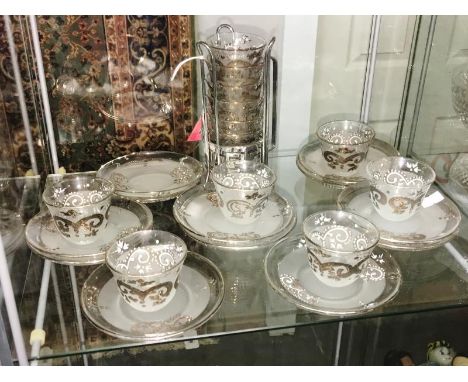 A quantity of glass coffee cups and saucers with white metal decoration.
