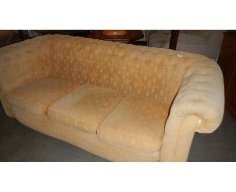 A cream upholstered Chesterfield sofa.