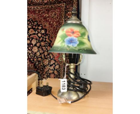 A table lamp with floral decorated glass shade.