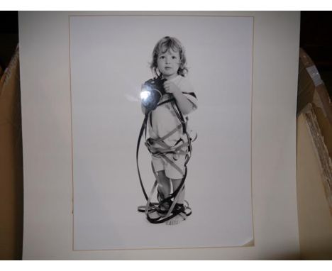 Nigel Fisher, a black and white photographic portrait of a child with a camera, signed on the mount, together with a quantity