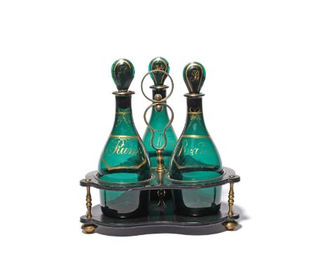 A set of three green glass decanters and stoppers in an ebonised wood frame, c.1800, of mallet shape, each decorated with a g