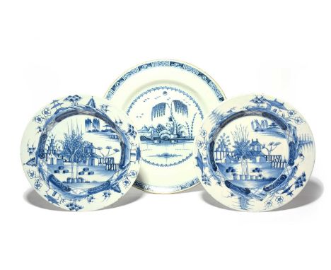 A pair of Dublin delftware large plates, c.1760, painted with small huts behind trees and cannon ball rocks, the rims with la