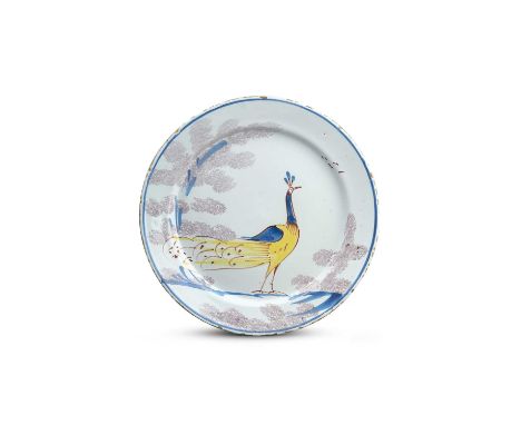 A Bristol delftware 'Farmyard' plate, c.1720-30, painted in yellow, blue and red with a strutting peacock between trees spong