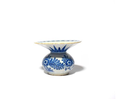 A delftware spittoon, c.1760, the rounded base painted in blue with large flowering plants, the deep flared rim with a trelli
