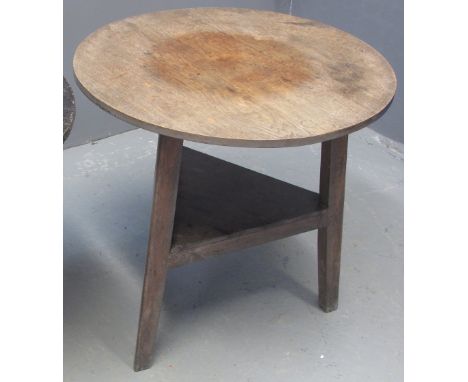 19TH CENTURY WELSH TRADITIONAL OAK CRICKET TABLE with planked circular top on triangular legs with triangular under shelf. 77