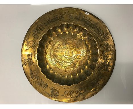 Antique Indian brass wall charger, Depicting king figure and servants to the centre, The outer rim depicts an army of figures