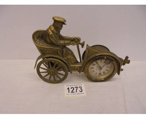 A vintage brass clock in the form of a veteran car with Toby Baxter movement, in working order. Movement at back missing 1 lo