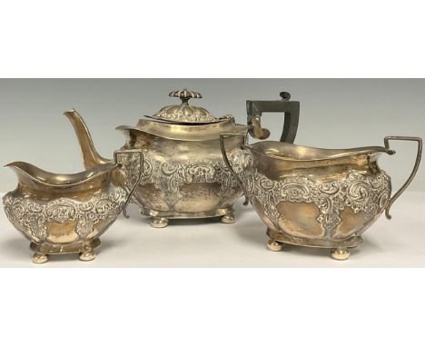 An Edward VII composed silver three-piece tea service, comprising teapot, sugar basin and cream jug, chased with flowers and 