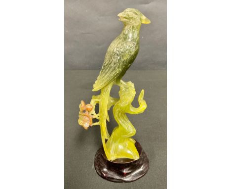 A carved Chinese jade figure of a bird, perched on a prunus blossom branch, hardwood stand, 20.5cm overall