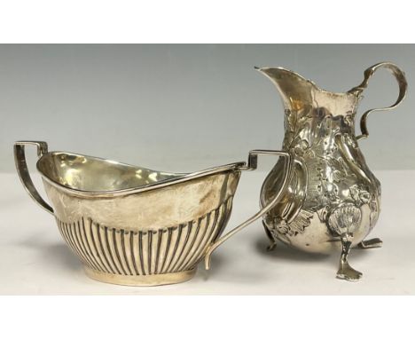 A George V silver half-fluted two-handled sugar basin, Birmingham 1924; a George III silver cream jug, chased with flowers an