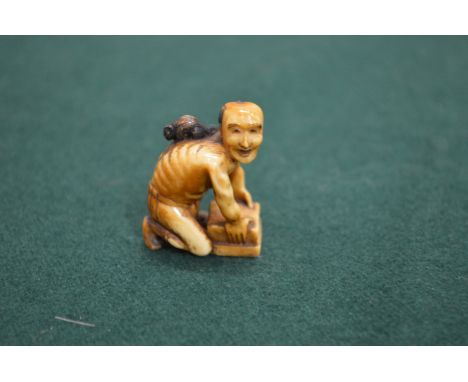 A small Japanese ivory netsuke of a crouching man.