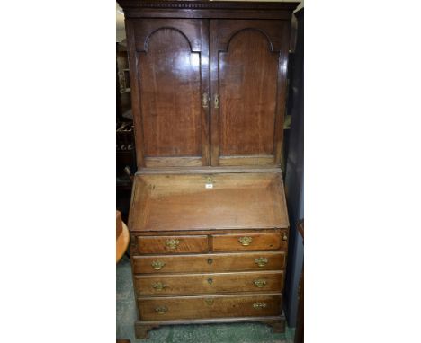 An 18th century oak bureau bookcase, dentil cornice, two arched panel doors to top, the fall front enclosing fitted interior,