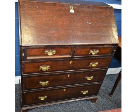 A George III oak bureau, fall front enclosing a small cupboard door, secret compartments, small drawers and pigeon holes, abo