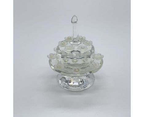 An exclusive jubilee edition for SCS members. A clear crystal cake on a stand with little frosted flowers around a single can