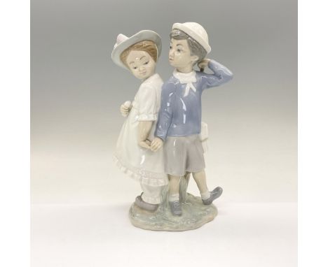 This porcelain figurine depicts a well-dressed boy and girl holding hands. Lladro backstamp to base. Glossy finish in the sub