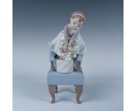 The 1998 Event Figurine from Lladro. Depicts a barefoot little girl standing on a blue armchair with two kittens in a basket.