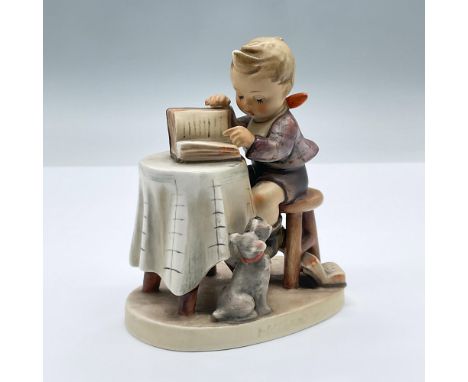 A charming figure of a seated boy reading a book on a table with a small dog beside him. Goebel Hummel backstamp. 306. Issued