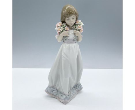 Glossy finished figural of a young girl holding two bouquets of pink and white flowers near her face. Lladro Collectors Socie