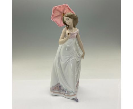 Glossy porcelain, features a delicate lady dressed in a white dress holding a pink parasol. Lladro backstamp. This item has i