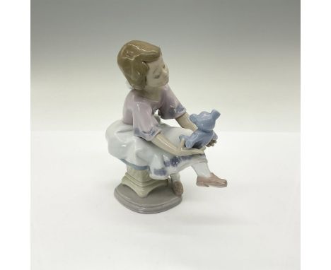Glossy finish figurine of a young girl holding her teddy bear. Lladro backstamp. Collectors Society Lladro. This item has its