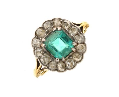 Emerald and diamond fifteen stone cluster ring, in unmarked yellow metal, circa 1910, the step cut emerald measuring approxim