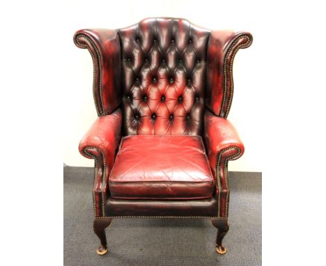 A button backed ox blood leather wing backed arm chair.