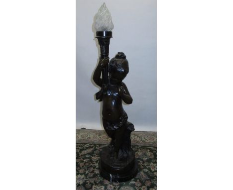 After Moreau; a large patinated hollow bronze floor lamp modelled as a cherub supporting a flaming torch, signed, on naturali