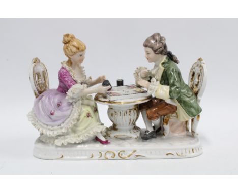 Continental porcelain figure group of a a man and woman playing backgammon, 26cm long 