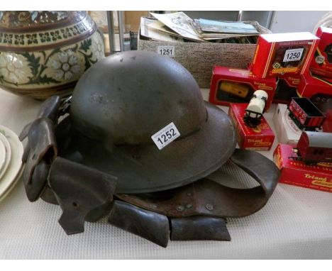 A civil defence grey Zukerman helmet marked 'L' with inner liner and a leather bandoleer belt