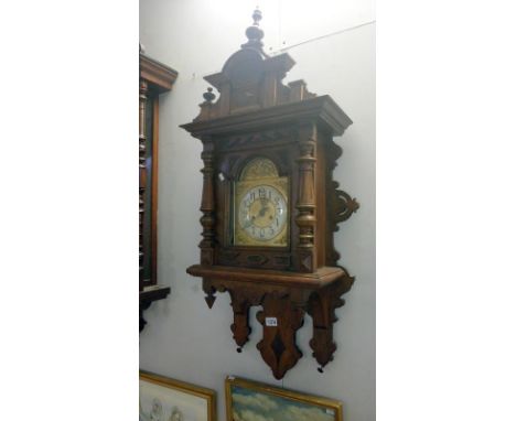 An oak wall clock with brass dial