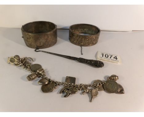 A mostly silver charm bracelet, a silver handled button hook and 2 silver bangles