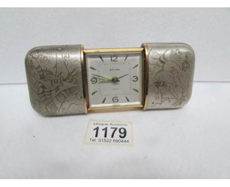 An Estyma sliding case travel clock with silver coloured case engraved with oriental fish