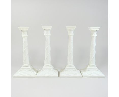A set of four mid 20th century Royal Worcester white glazed porcelain candlesticks, each relief decorated with swags, green p