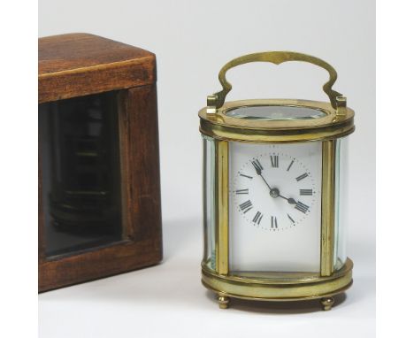 An early 20th century French brass cased carriage clock, of oval shape, with a white enamel dial, in a fitted travelling case