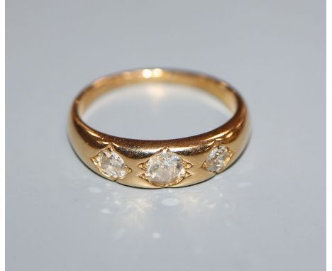 An 18ct. gold three stone gypsy set diamond ring, size N/O.